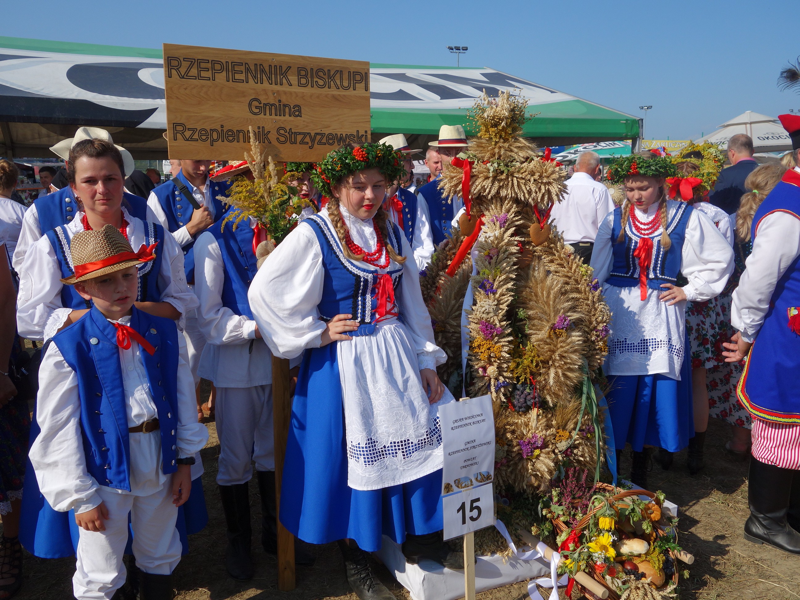 grupa osób w strojach ludowych przy wieńcu dożynkowym z Rzepiennika Biskupiego